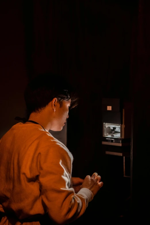 a man standing in front of a tv in a dark room, vending machine, checking her phone, asian man, coffee machine