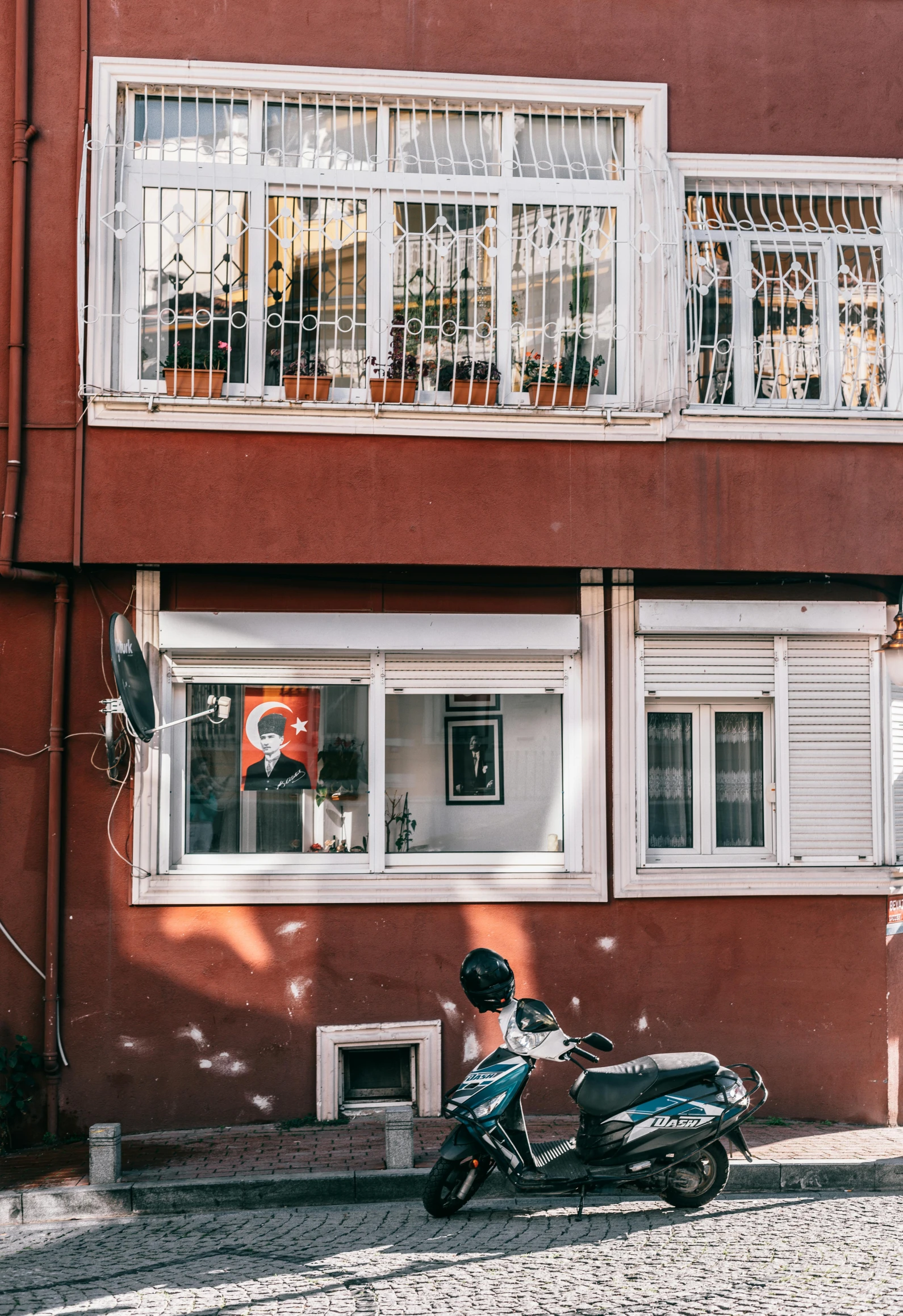 a man riding a scooter down a cobblestone street, a picture, inspired by Elsa Bleda, pexels contest winner, art nouveau, red building, istanbul, windows and walls :5, apartment