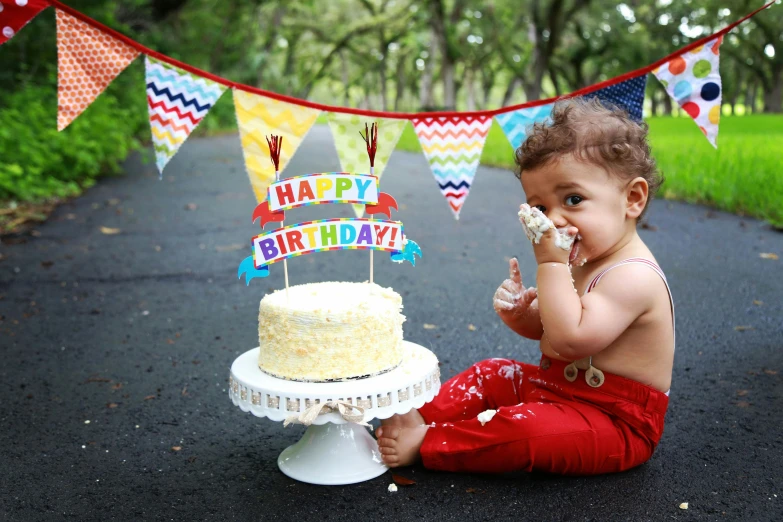 a baby sitting in front of a birthday cake, a photo, by Helen Berman, pexels, graffiti, red pennants, avatar image, figurines, high quality product image”