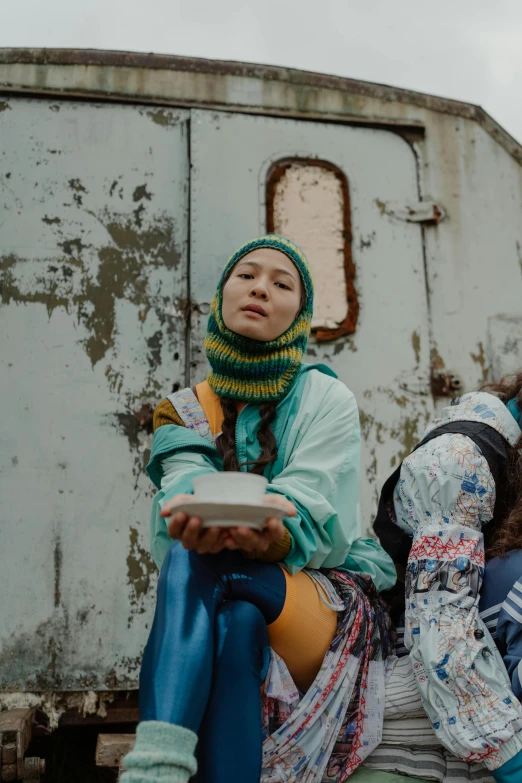 a group of women sitting next to each other, an album cover, by Adam Marczyński, trending on unsplash, graffiti, wearing a head scarf, offering a plate of food, russian clothes, still from the film