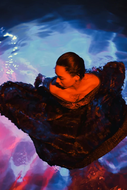 a woman in a black dress floating in a pool, an album cover, unsplash, renaissance, tessa thompson, lit up, floating robes, performance
