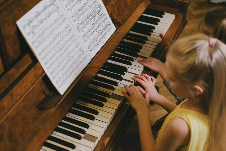 a little girl that is playing a piano, pexels, birdseye view, private school, finely textured, lit from the side