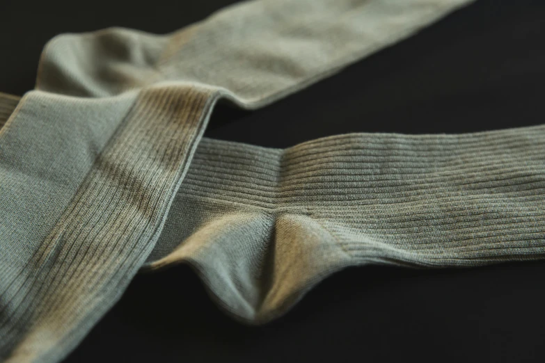 a pair of socks sitting on top of a table, by David Simpson, unsplash, renaissance, fine texture detail, sage green, high detail shot, on grey background