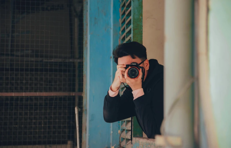 a man taking a picture of himself with a camera, a picture, by Alejandro Obregón, pexels contest winner, looking around a corner, coloured photo, short telephoto, looking directly at the camera