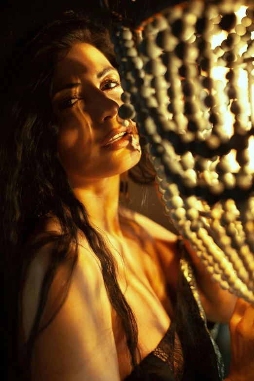 a woman standing in front of a chandelier, inspired by Elsa Bleda, renaissance, wet shiny skin, freida pinto, bathed in golden light, ropes and chains