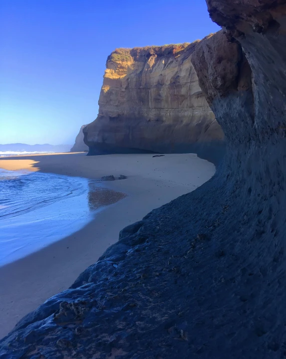 a man riding a surfboard on top of a sandy beach, an extremely large cave, te pae, profile image, snapchat photo