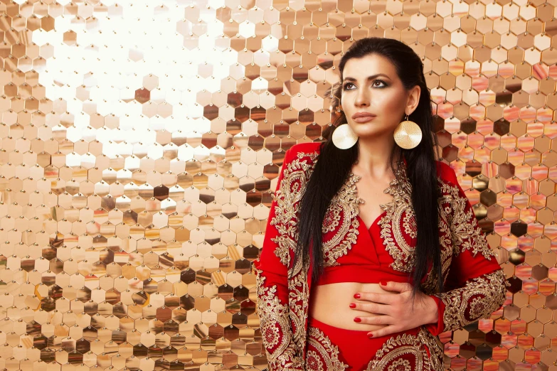 a woman in a red outfit posing for a picture, an album cover, arabesque, gold jewellery, patterned clothing, shot on sony a 7, portrait image