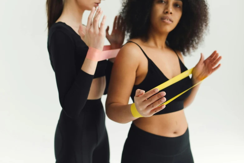 a couple of women standing next to each other, trending on pexels, renaissance, workout, tape, yellows and blacks, reaching out to each other