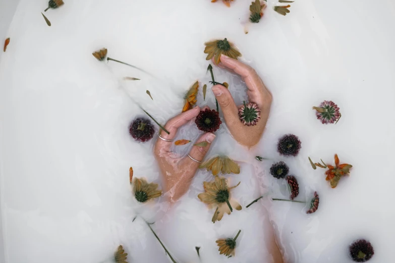 a person laying in a bath filled with flowers, trending on pexels, process art, holding each other hands, floating objects, nature photo, plastic skin