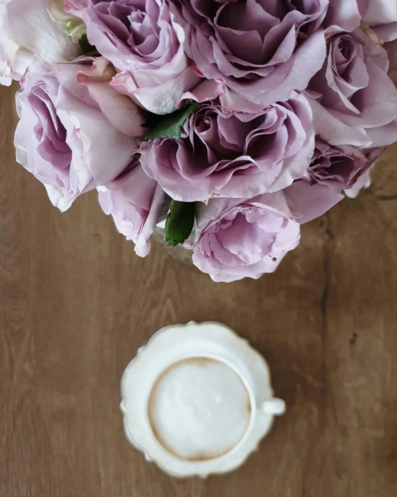 a vase filled with pink roses next to a cup of coffee, by Alice Mason, unsplash, on a wooden plate, lilac, silver，ivory, milk