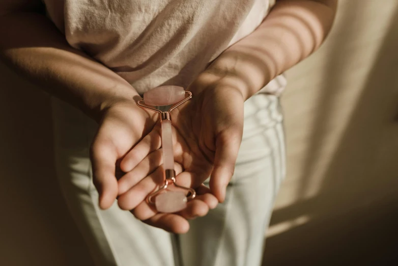 a woman holding a hourglass in her hands, a marble sculpture, by Emma Andijewska, trending on pexels, minimalism, diamond and rose quartz, clay amulets, rose gold, seaglass