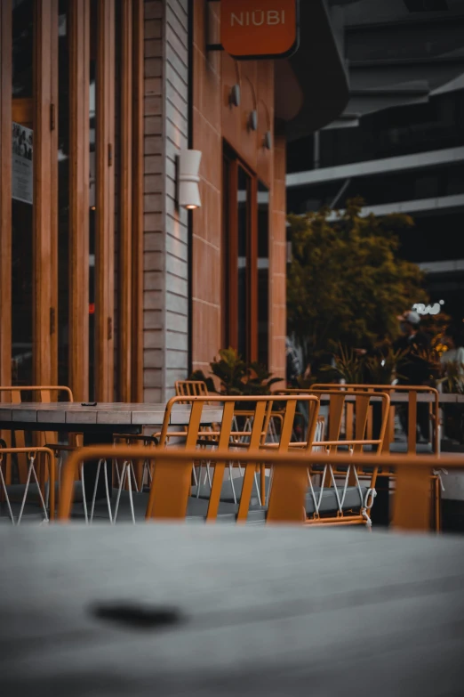 a row of orange chairs sitting in front of a building, by Lee Loughridge, unsplash, cafe tables, in chippendale sydney, it's getting dark, sittin