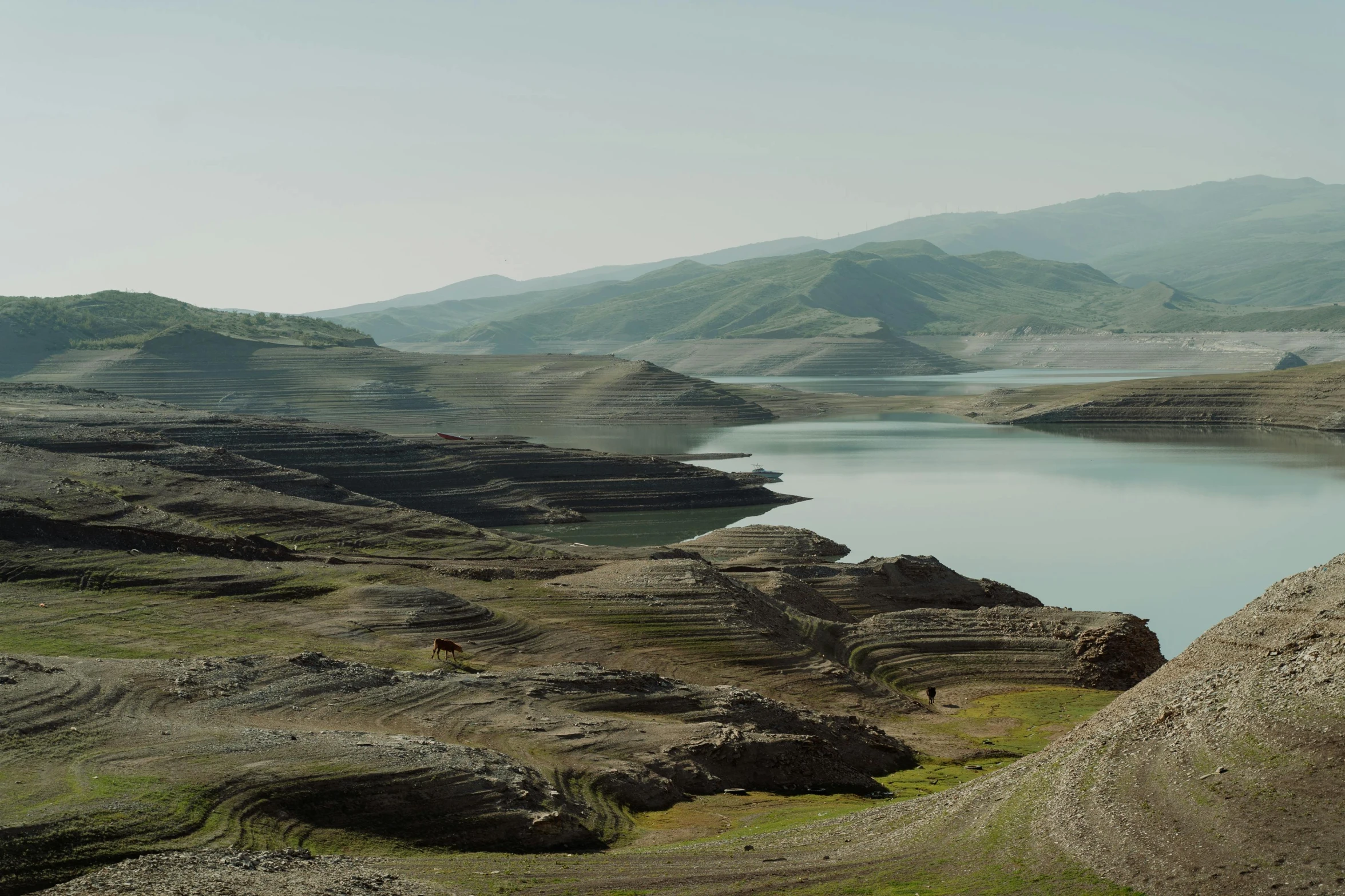 a large body of water surrounded by mountains, by Muggur, erosion algorithm landscape, documentary photo, nekro petros afshar, near a lake