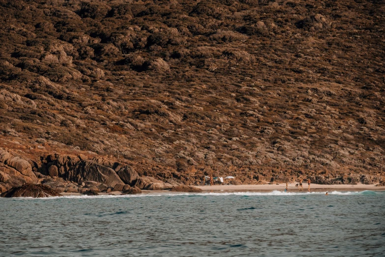 a group of people riding surfboards on top of a sandy beach, pexels contest winner, australian tonalism, greece, 2 5 6 x 2 5 6 pixels, in the distance is a rocky hill, brown