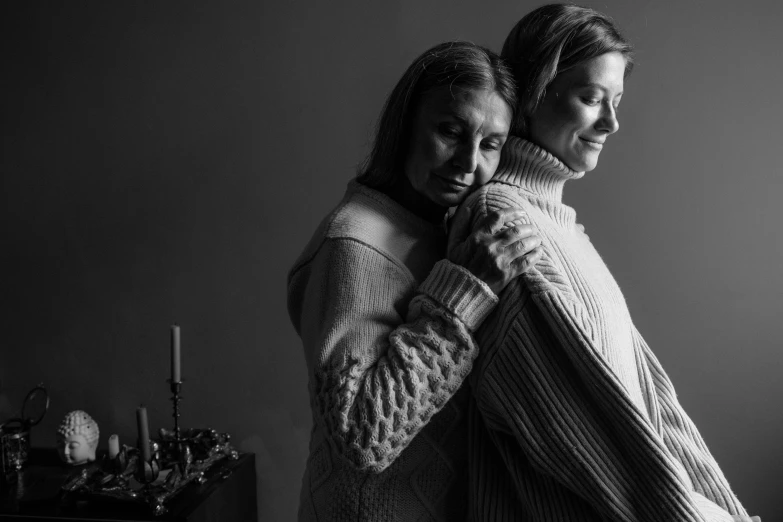 a couple of women standing next to each other, a black and white photo, by Dan Frazier, pexels, renaissance, wearing sweater, hugging and cradling, home photography portrait, medium format