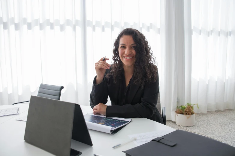 a woman sitting at a table in front of a laptop computer, wearing black business suit, yan morala, holding a staff, profile image