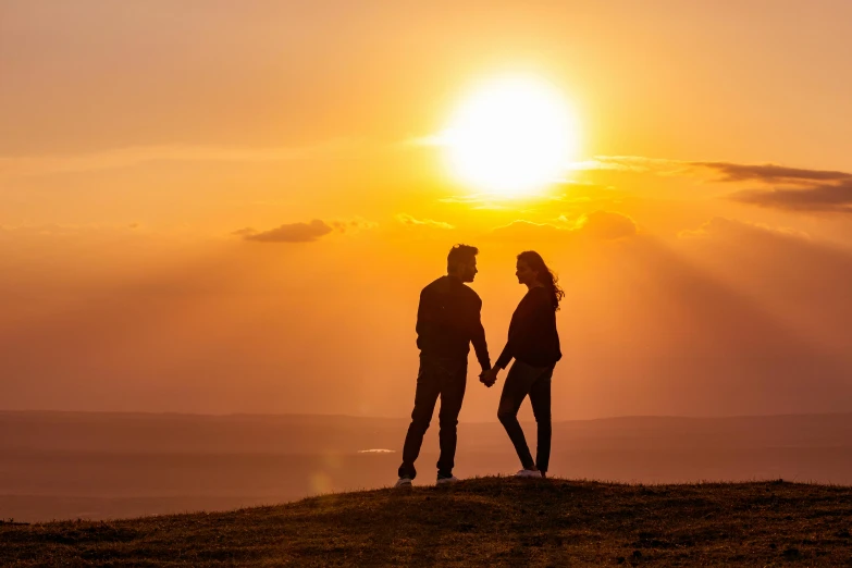 two people standing on top of a hill holding hands, by Julian Hatton, pexels contest winner, romanticism, gorgeous romantic sunset, male and female, shot on 1 5 0 mm, looking cute