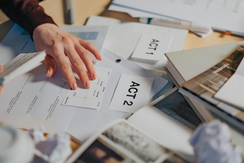 a person sitting at a table with papers and a pen, by Julia Pishtar, unsplash, process art, placards, aerial shot, actors, lachlan bailey