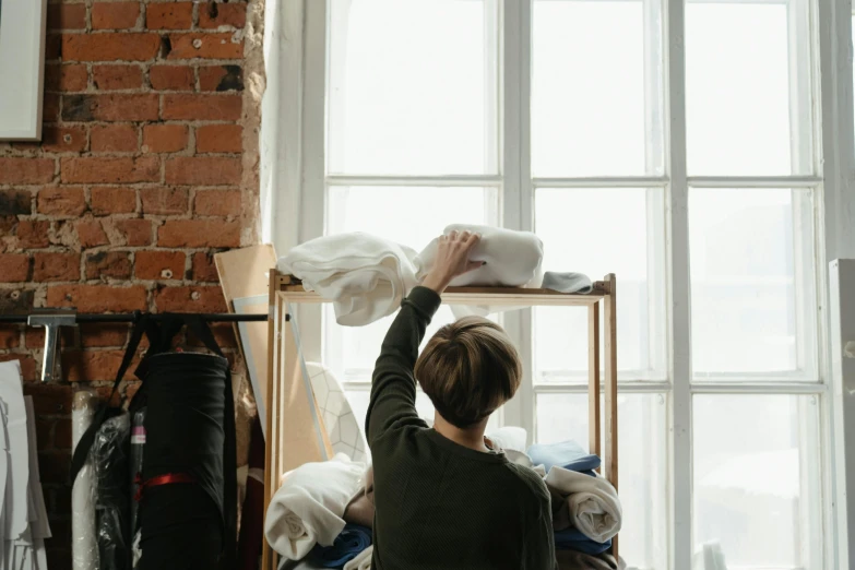 a woman that is standing in front of a window, inspired by Sarah Lucas, pexels contest winner, happening, furniture overturned, crafting, bedhead, interior of a loft