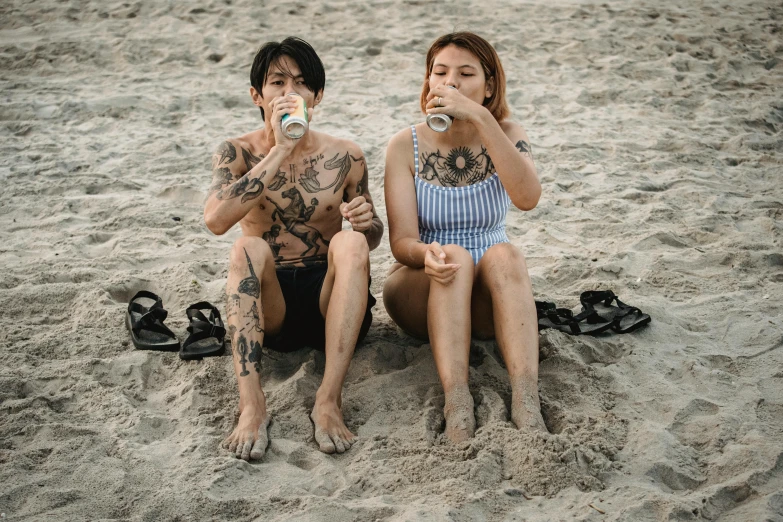 a couple of people sitting on top of a sandy beach, a tattoo, pexels contest winner, cold brew coffee ), of taiwanese girl with tattoos, half body photo, full body tattoo