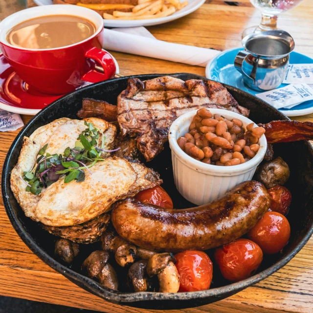 a plate of food sitting on top of a wooden table, by Joe Bowler, hearty breakfast, beans, shepherd's crook, in a red dish