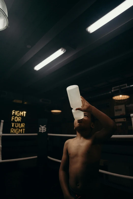 a man standing in a boxing ring holding a bottle, by Jacob Toorenvliet, pexels contest winner, spilled milk, bleached strong lights, gif, ( ( theatrical ) )