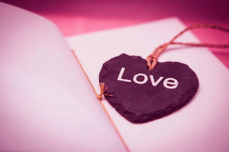 a black heart with the word love written on it, an album cover, by Julia Pishtar, unsplash, romanticism, ((pink)), notebook, low-angle, holiday