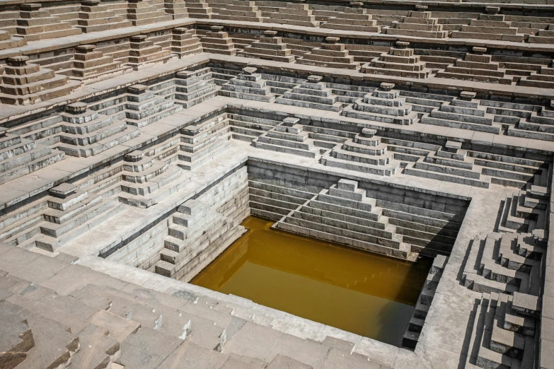 a well in the middle of a brick structure, pexels contest winner, land art, hindu aesthetic, deep clear pools of water, square lines, staggered terraces