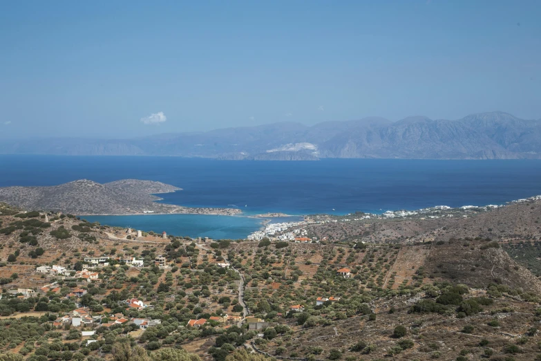 a large body of water sitting on top of a lush green hillside, by Exekias, pexels contest winner, hurufiyya, small port village, islands on horizon, gelios lens, athmospheric