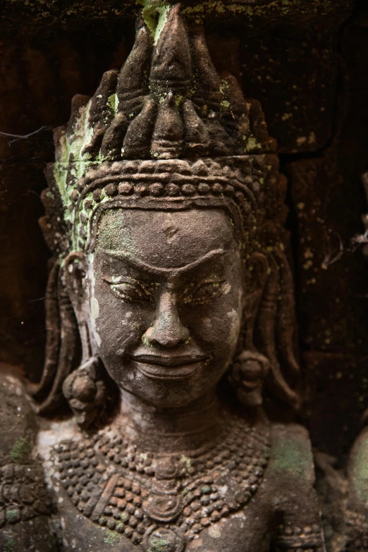 a close up of a statue of a person, angkor wat, facing the camera, ornate carved architecture, mossy head