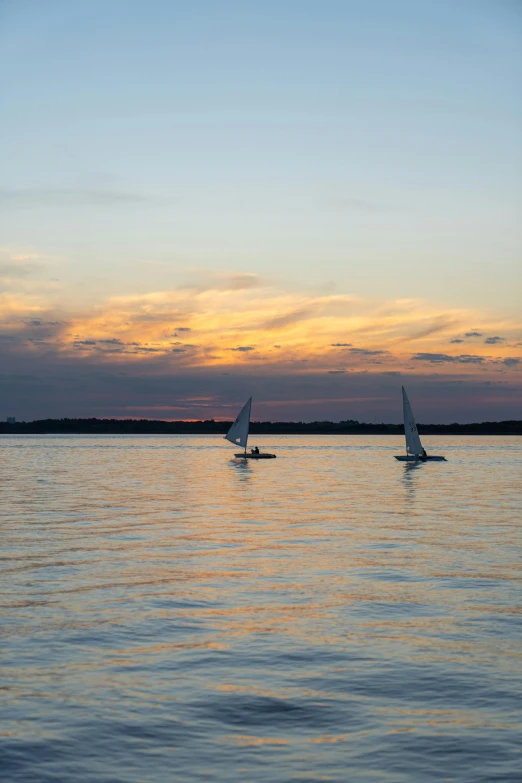 a couple of sailboats floating on top of a body of water, flickr, late summer evening, high quality photo, minn, light show