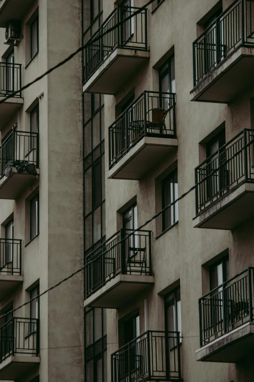 a tall building with balconies and balconies on the balconies, inspired by André Kertész, pexels contest winner, beige and dark atmosphere, ( ( railings ) ), concrete ), porches