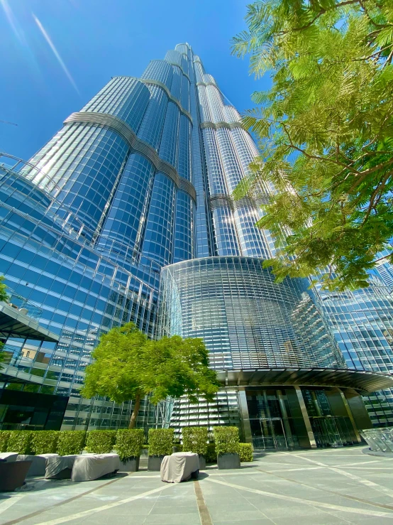 a very tall building with a lot of windows, ameera al taweel, with shiny glass buildings, thumbnail, gardens and fountains