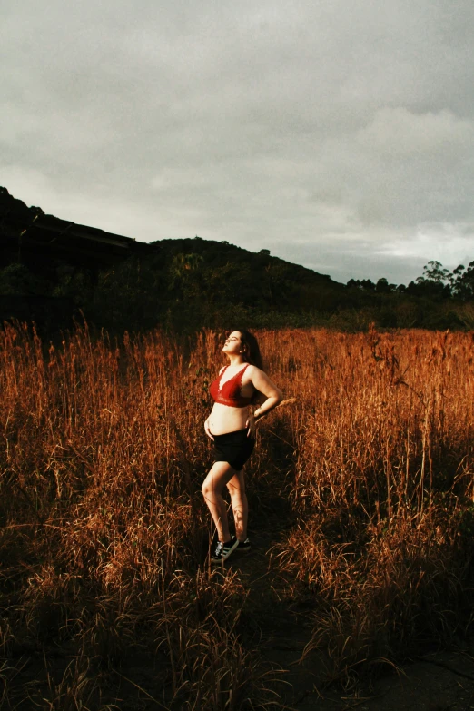 a woman running through a field of tall grass, an album cover, unsplash, pregnant belly, in australia, panoramic view of girl, evening