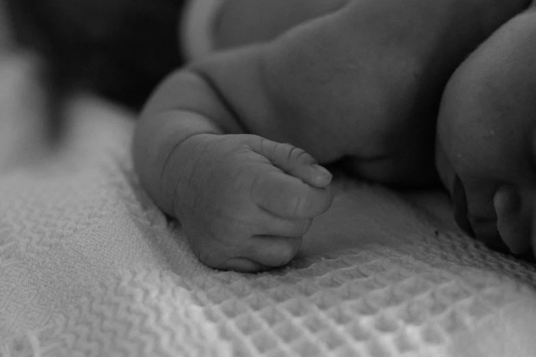 a black and white photo of a sleeping baby, a black and white photo, by Caroline Mytinger, pexels, symbolism, detailed close foot shot, bump in form of hand, hatching, the birth