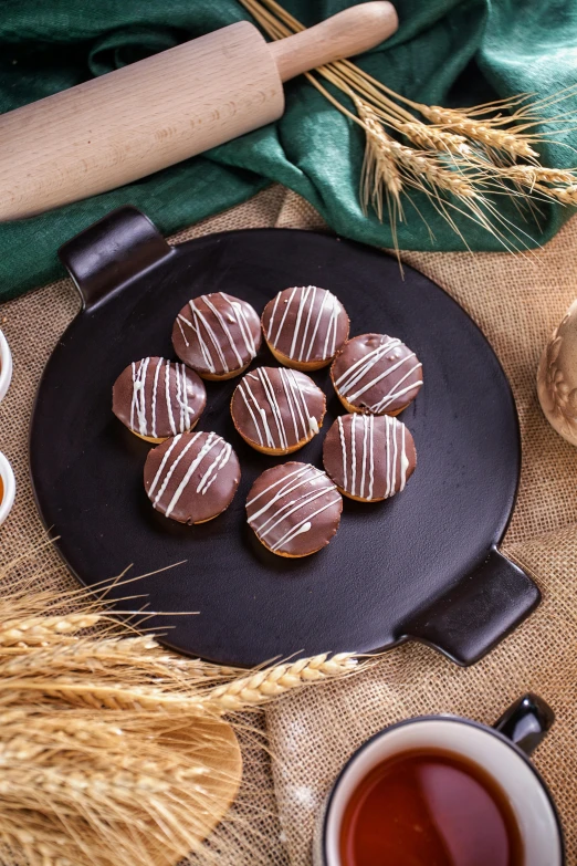 a plate topped with chocolate covered donuts next to a cup of tea, inspired by Károly Patkó, dribble, 6 pack, chalkboard, 8 k ), loaves