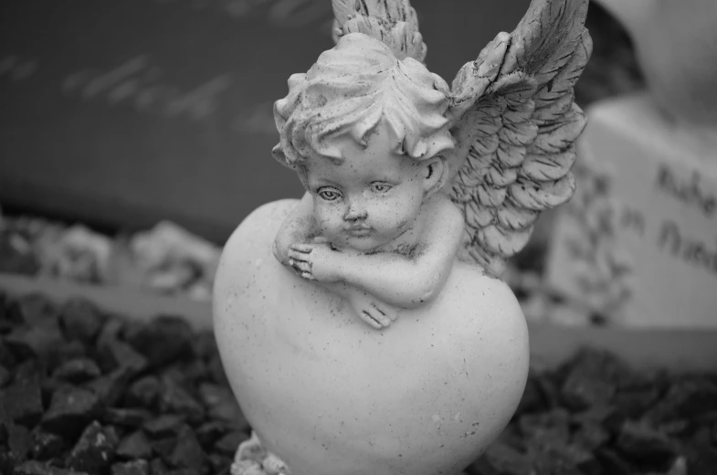 a black and white photo of an angel figurine, a statue, by Charmion von Wiegand, concrete art, bashful expression, cranberry statue, eros, valeriy vegera