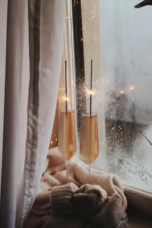 a couple of champagne flutes sitting on top of a window sill, a still life, by Julia Pishtar, unsplash, magical realism, golden meteors, ivory and copper, holiday season, long trunk holding a wand