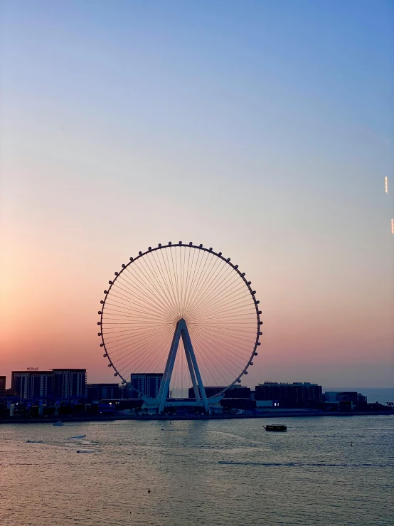 a large ferris wheel sitting in the middle of a body of water, by Robbie Trevino, hurufiyya, dubai, at golden hour, high quality image”