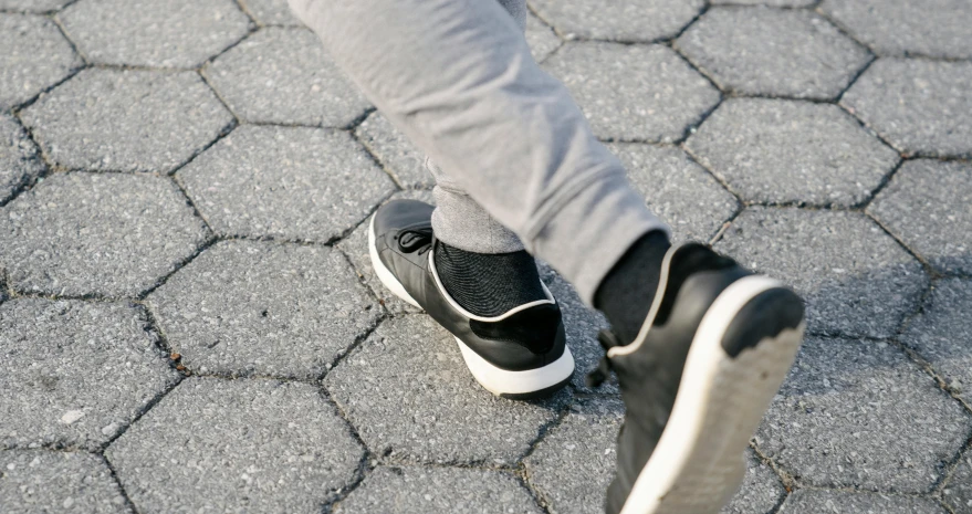 a close up of a person's feet on a skateboard, a stipple, by Niko Henrichon, trending on unsplash, happening, grey pants and black dress shoes, tights; on the street, running shoes, foot wraps