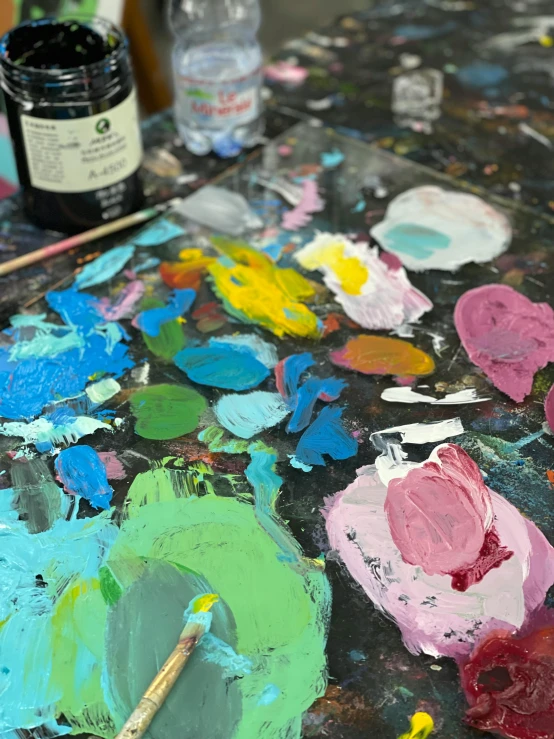 a close up of a paint palette on a table, an impressionist painting, inspired by Hans Hofmann, trending on unsplash, process art, cyan and magenta, black paint, 🎨🖌, inside a grand messy studio