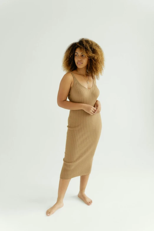 a woman standing in front of a white background, by Carey Morris, bodycon dress, light brown colors, chill, sustainable materials