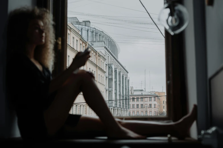 a woman sitting on a window sill reading a book, by Emma Andijewska, pexels contest winner, saint petersburg, connecting lines, grey sky, afternoon hangout