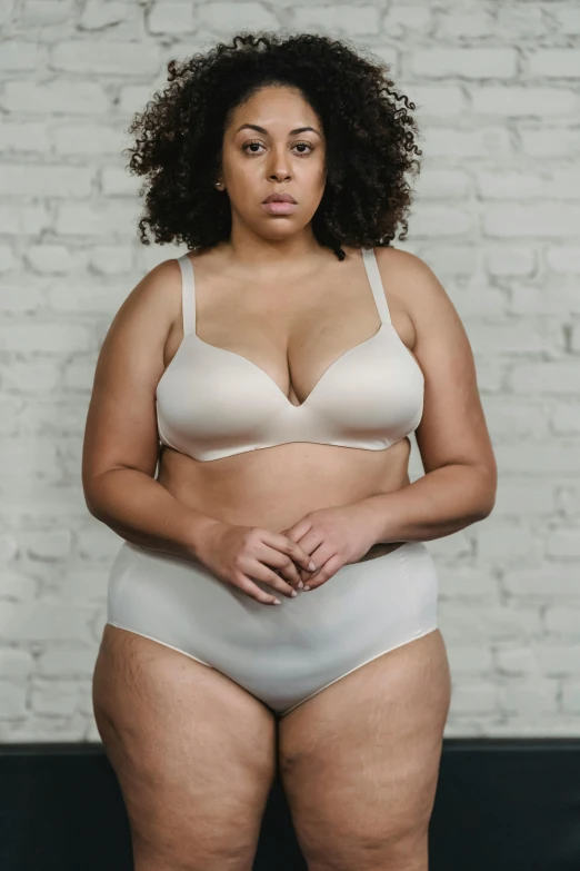 a woman in white underwear standing in front of a brick wall, inspired by Vanessa Beecroft, trending on pexels, bbw, beige mist, person in foreground, wearing bra