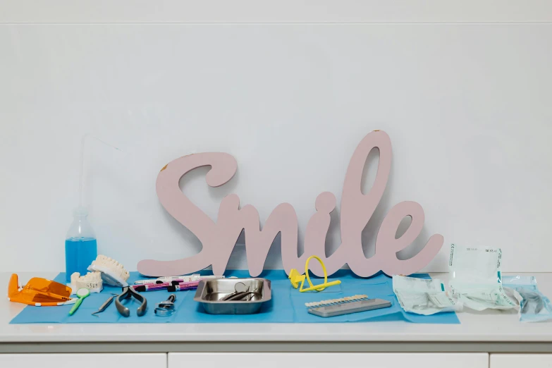 a close up of a table with a sign on it, a still life, by Rachel Reckitt, international typographic style, big smile white teeth, surgical supplies, pink, panoramic shot
