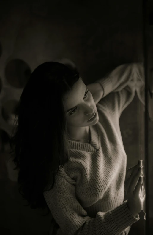 a black and white photo of a woman looking out a window, inspired by Yousuf Karsh, pexels contest winner, black haired girl wearing hoodie, chiaroscuro painting, soft light.4k, old sepia photography