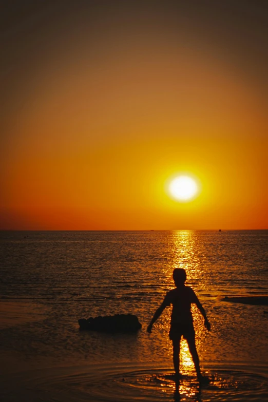 a person standing in the water at sunset, red sea, ((sunset)), family friendly, day setting