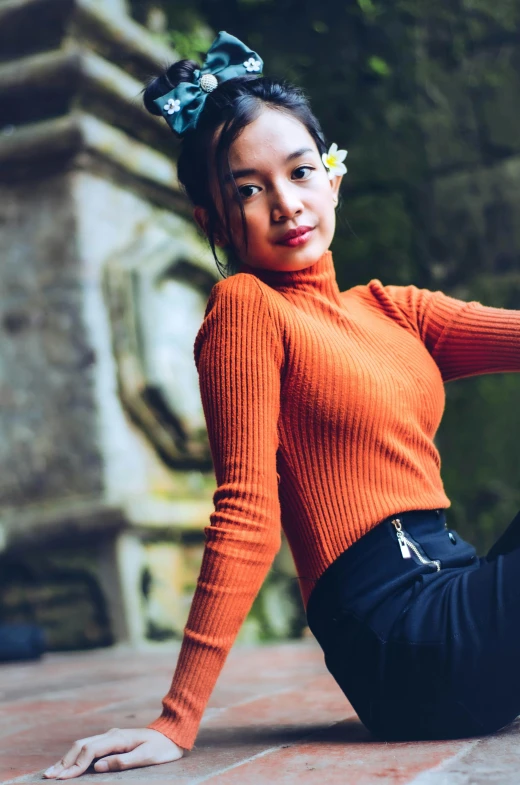 a woman sitting on the ground posing for a picture, pexels contest winner, renaissance, wearing turtleneck, kiko mizuhara, orange color, wearing a cute top