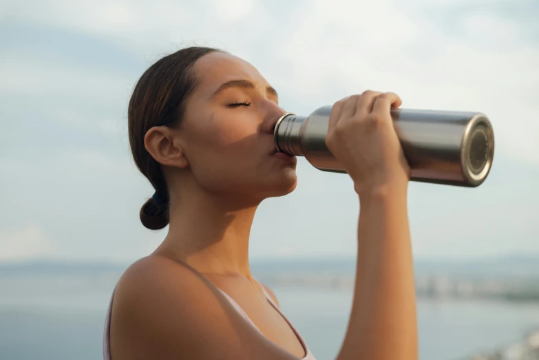 a woman drinking out of a water bottle, trending on pexels, taned skin, stainless steel, avatar image, silo