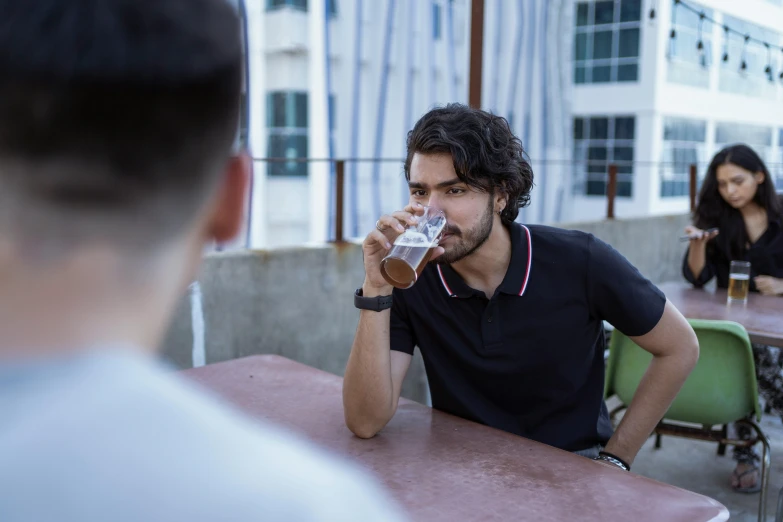 a man sitting at a table drinking from a glass, pexels contest winner, aboriginal australian hipster, young greek man, in a rooftop, profile image